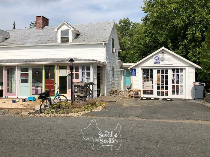 front view of DIY sunroom made from brightly colored vintage doors next to another small building with glass doors with bicycle mailbox and pea gravel lawn