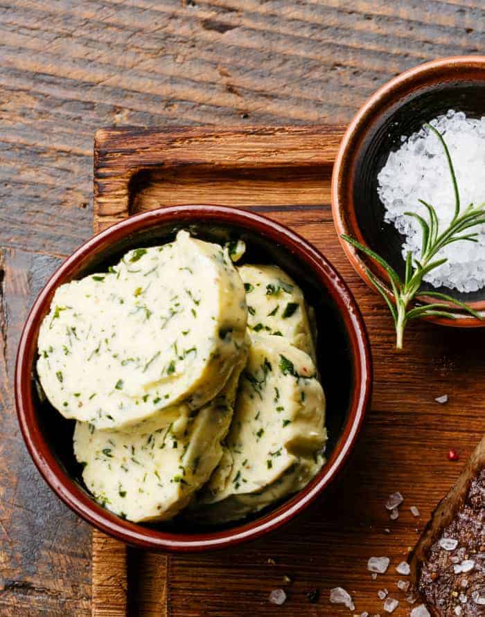 9 Compound Butter Recipes for Steak, Chicken or Fish Sliced grilled steak Ribeye with herb butter on cutting board on wooden background