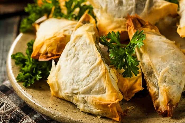 Easy Spanakopita spanakopita or spanikopita on a plate with a bright green parsley garnish