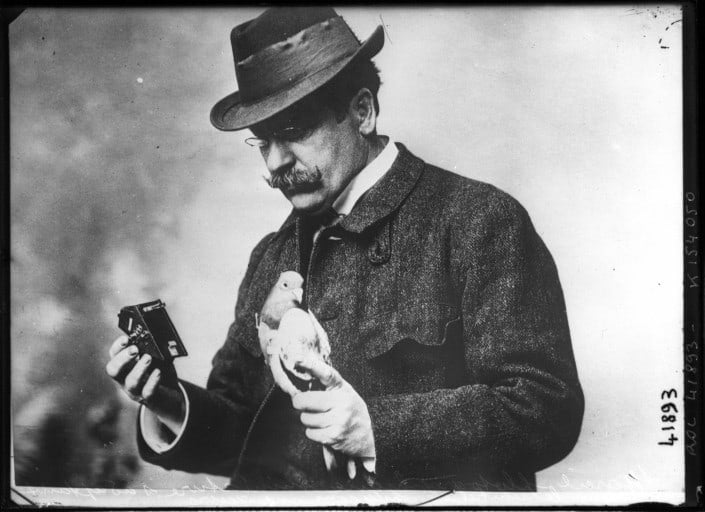 Julius Neubronner holding a homing pigeon and one of his cameras, 1914.
