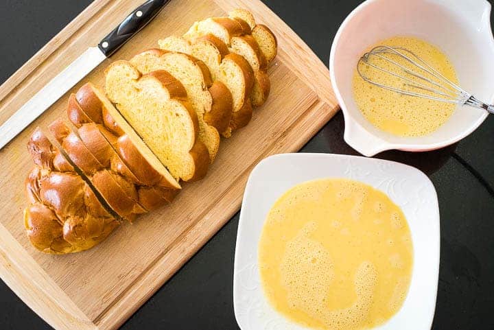 Sliced brioche next to a mixing bowl and a plate with custard for vanilla french toast.