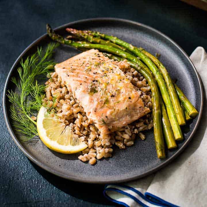 Lemon Dill Salmon and Asparagus Lemon dill salmon and asparagus plated with farro on a gray plate.