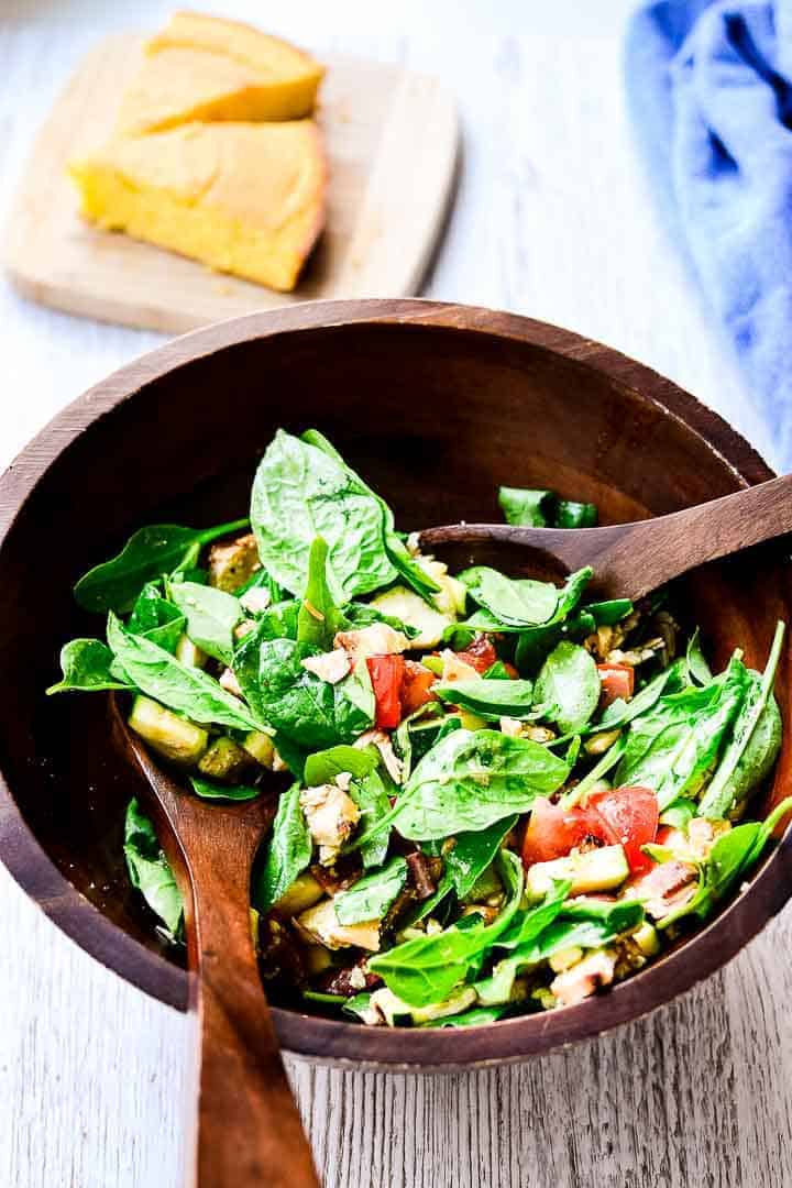 Wooden serving bowl filled with Carolina BBQ Chicken Salad with cornbread on a cutting board in the background.