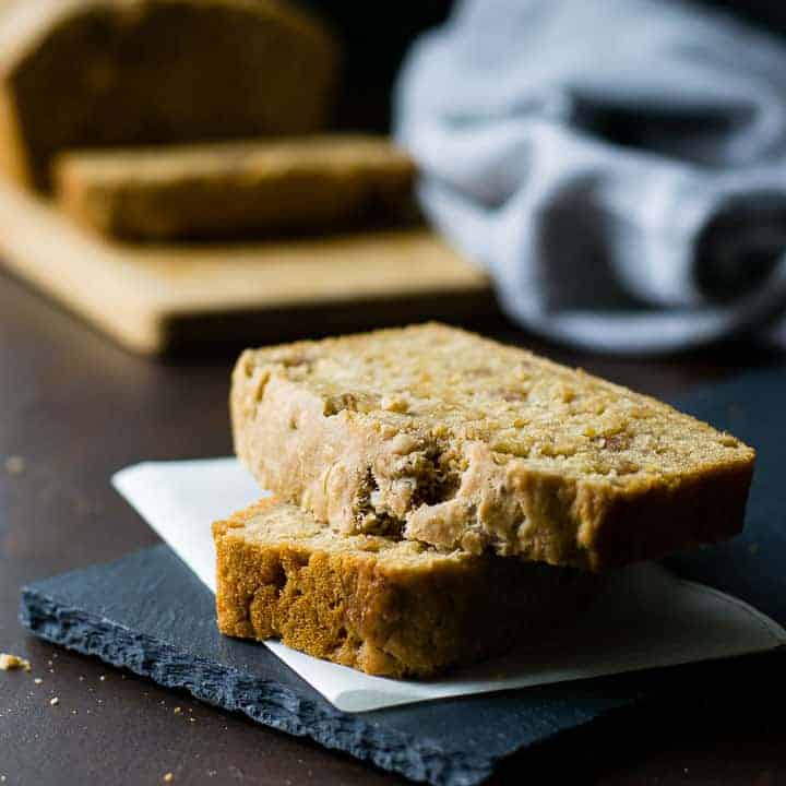 Two stacked slices of cheddar sausage Guinness beer bread on a piece of folded parchment on top a slate board.