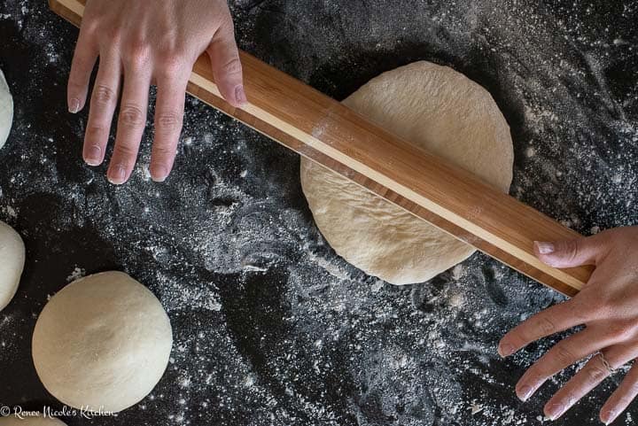 Rolling out rounds of pita dough.