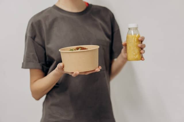 vrouw houdt een kom met voedsel en een shake vast