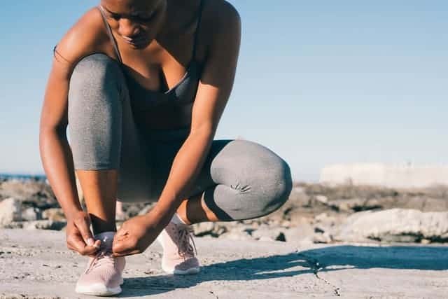 une femme en tenue de sport attache sa chaussure