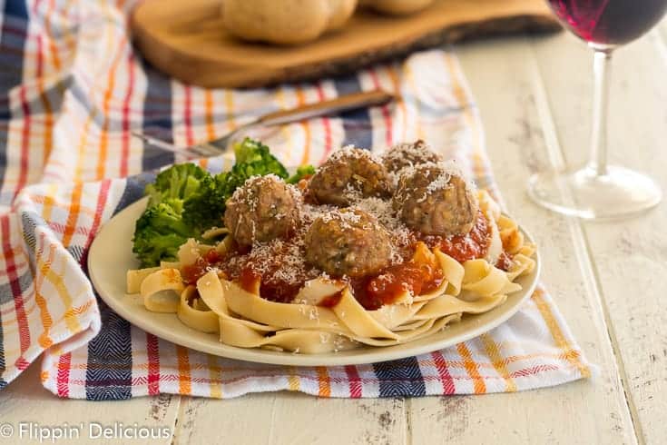 plate filled with gluten free pasta topped with marinara sauche and gluten free baked turkey meatballs, sprinkled with grated parmesan cheese.