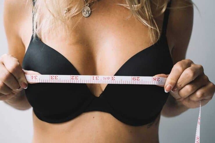 Frau misst ihre Brüste mit einem Zentimeter