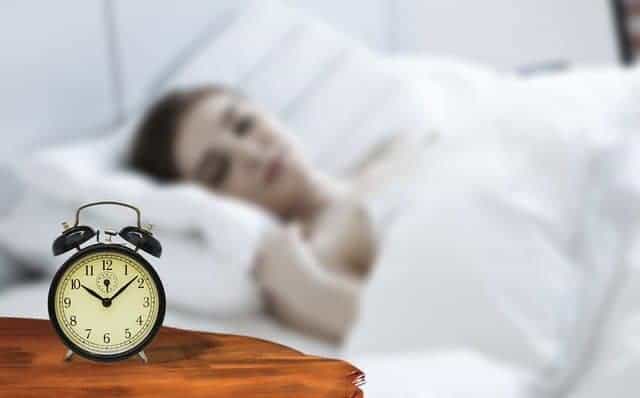 una donna addormentata con una sveglia accanto al letto