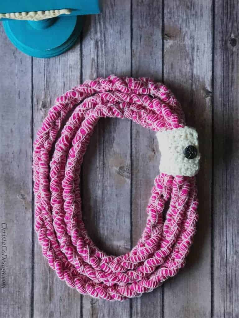 picture of magenta chunky yarn necklace wrapped in white contrast button