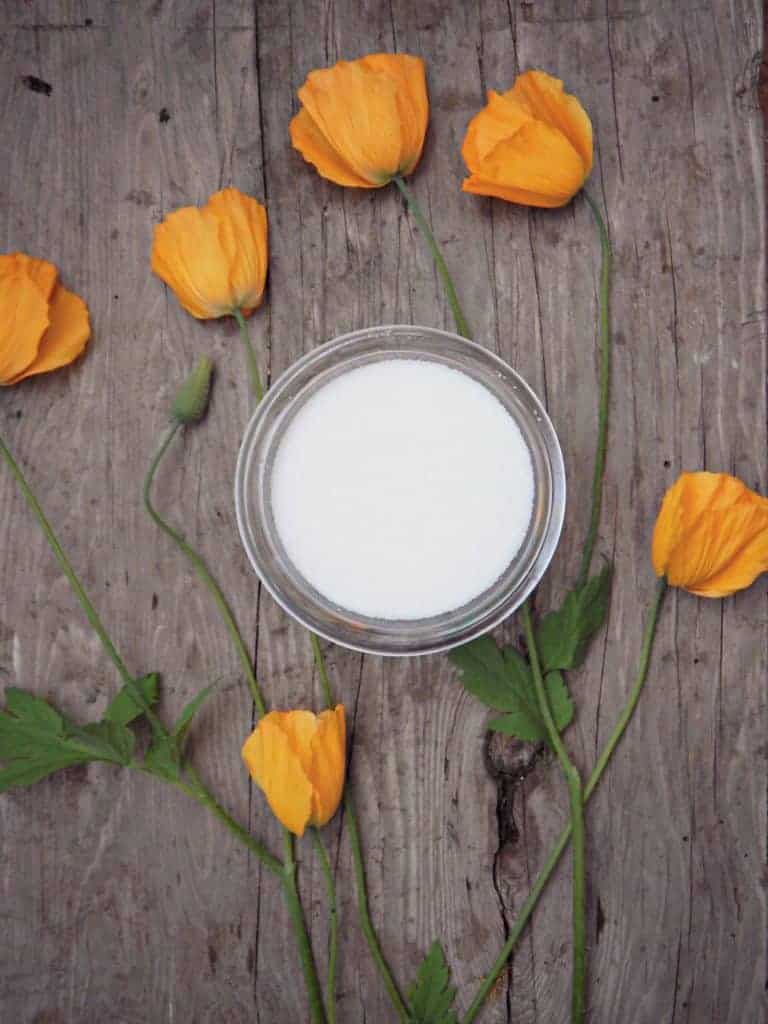 white sugar on wood table with orange flowers beside it