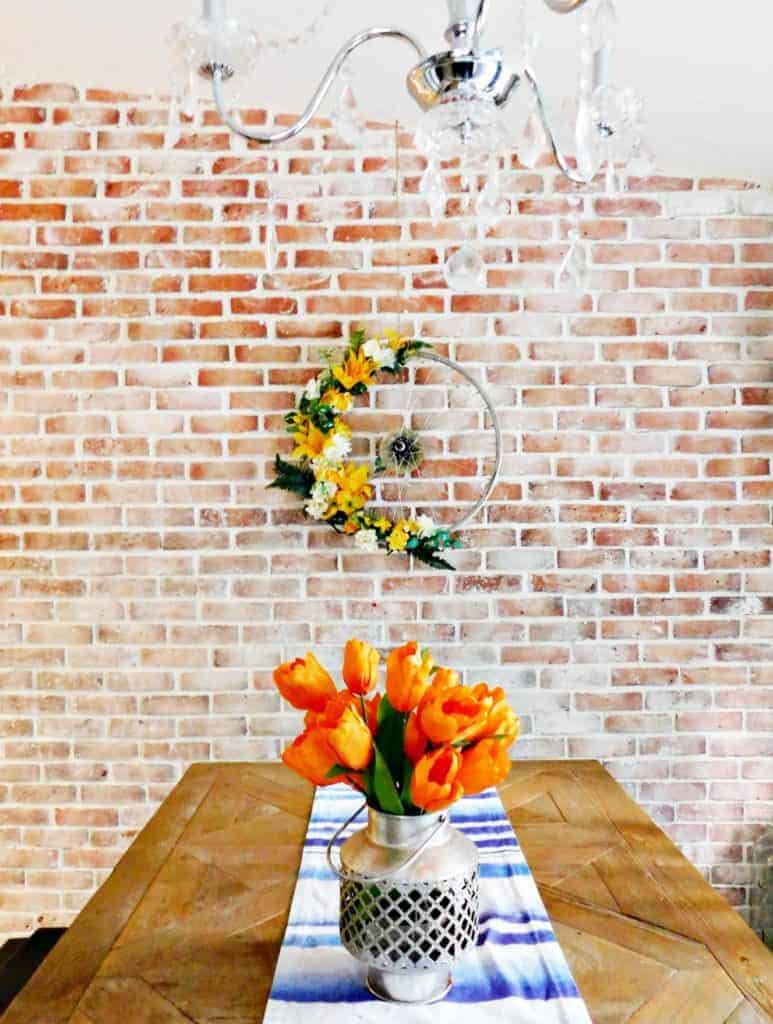 Bicycle Wheel Wreath yellow flowers on brick wall above dinner table