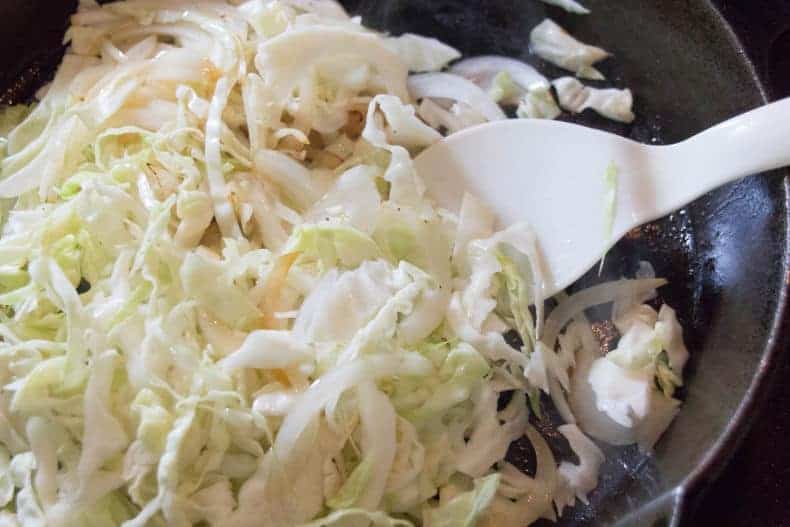 Cabbage noodles and sliced onion cook in the meat juices leftover in the cast iron pan.