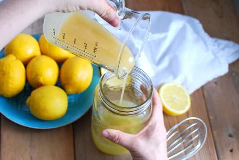 pouring melted honey into a quart jar to make lemonade