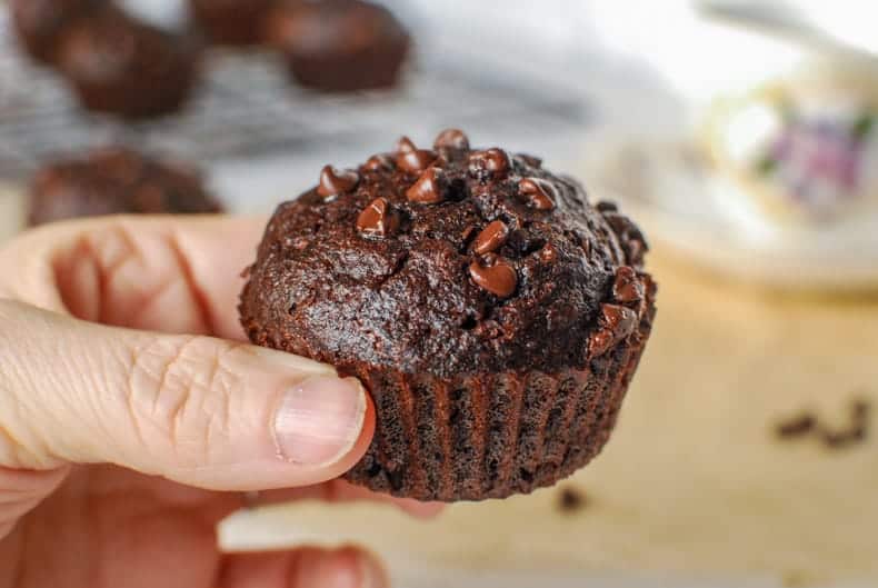 a close up shot of a coconut flour chocolate muffin being held up to the camera