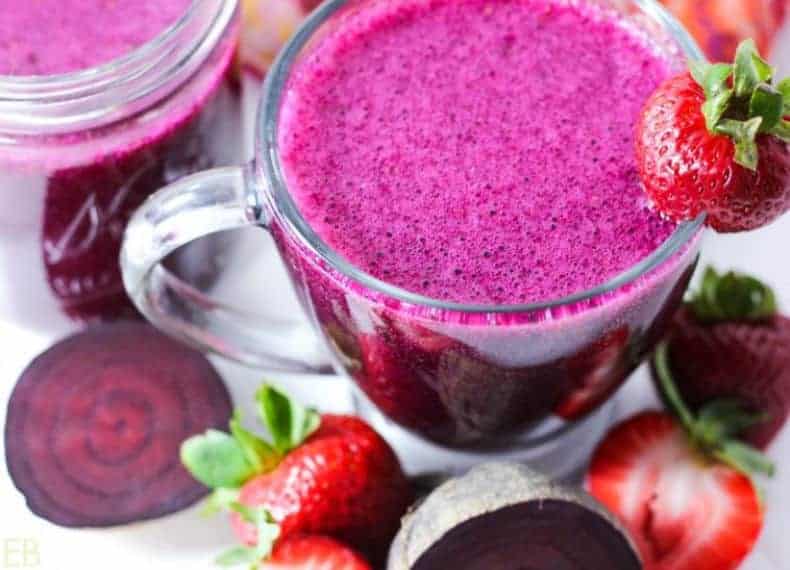 bright pink strawberry kvass drink in a mug with strawberries around it