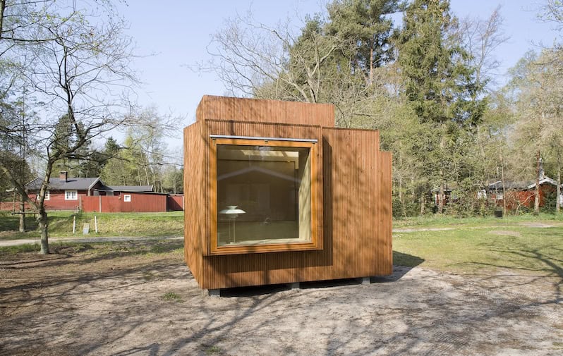 tiny-haus-hype-LIVEE Das Bild zeigt ein Tiny Haus auf einem Grundstück. Zu sehen ist das großes Fenster mit einer Holzfassade