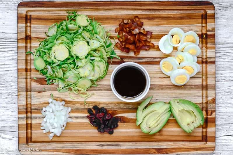 Ingredients for Shaved Brussels Sprouts Salad laid out on a two tone cutting board.