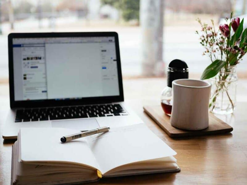 A photo of a laptop and a notebook. Photo by Nick Morrison on Unsplash
