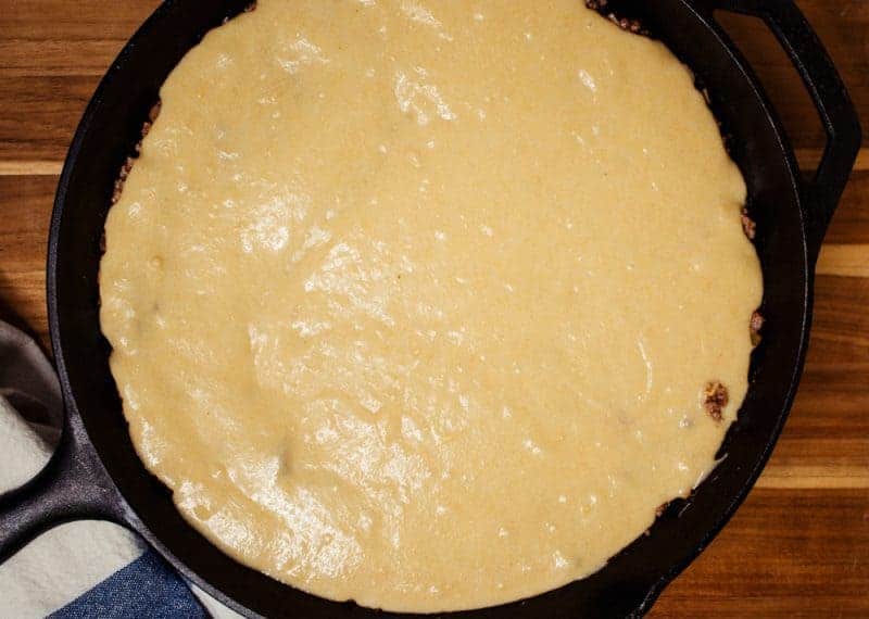 Easy Beef Tamale Pie in a Cast Iron Skillet topped with cornbread ready to go in the oven