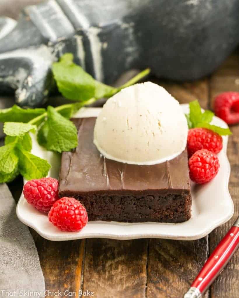 Fudgy Chocolate Sheet Cake with Cocoa Icing - A delectable, ultra-chocolate dessert that feeds a crowd! #sheetcake #chocolate Ice cream topped Fudgy Chocolate Sheet Cake with Cocoa Icing on a white dessert plate