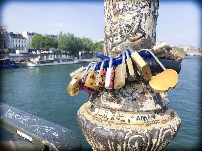 Pont des Arts during a visit of 3 days in Paris. A view of padlocks on a bike chain, around one of the posts on the bridge in the foreground. In the background is the River Seine.