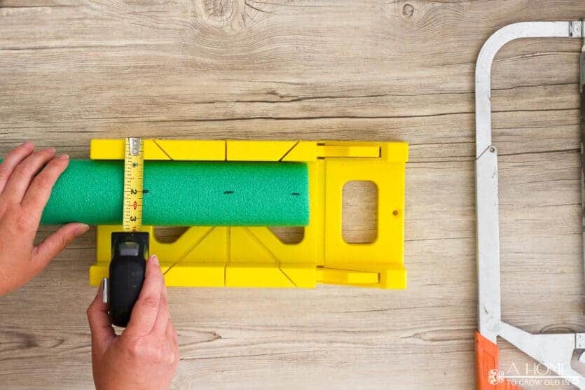 marking a pool noodle to be cut with a miter box to make a wreath