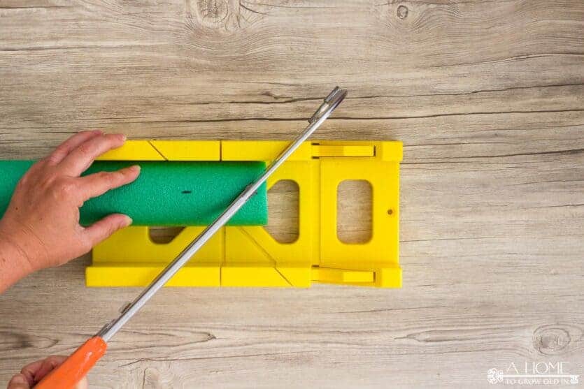cutting a pool noodle with a miter box to make a wreath