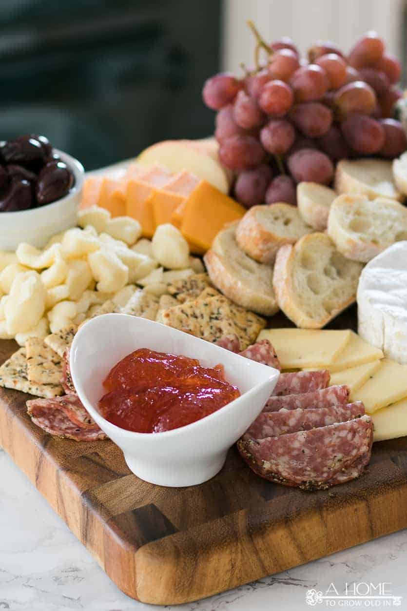 pepper jam in a bowl surrounded by cheese and crackers on a cheese board