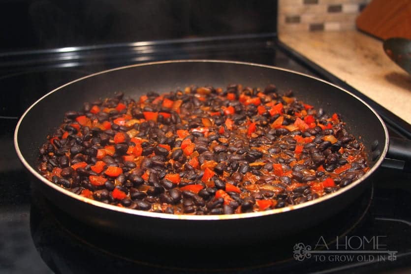 Mexican black beans sautΓ©ing on the stove