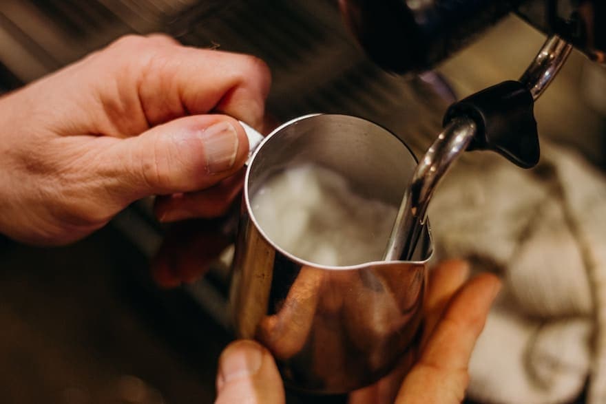 Hands frothing milk for coffee