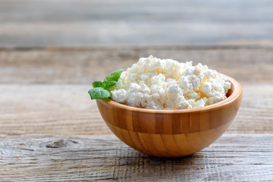 Cottage cheese in a wooden bowl on a wooden table
