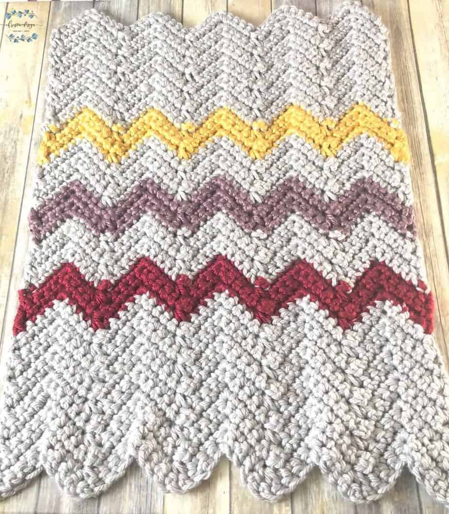 picture of jumbo yarn blanket in sliver, yellow, purple, red chevron stripes