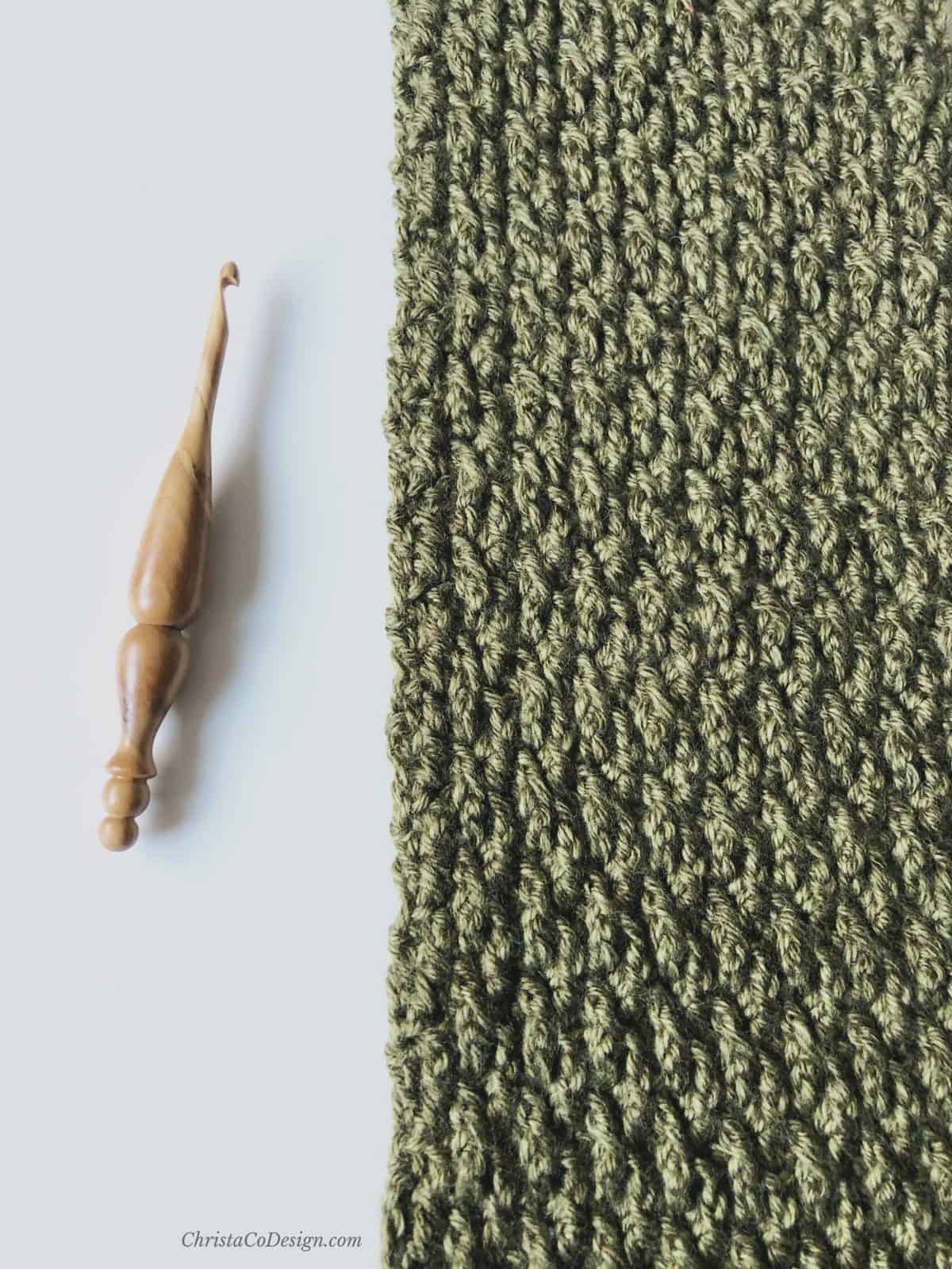 picture of wooden crochet hook and textured crochet scarf in green