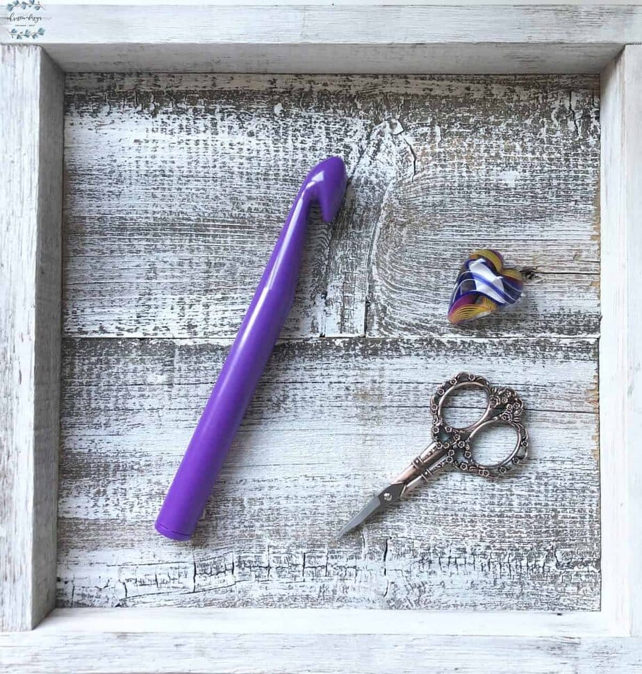 picture of large purple crochet hook on white square with vintage scissors in copper and glass heart