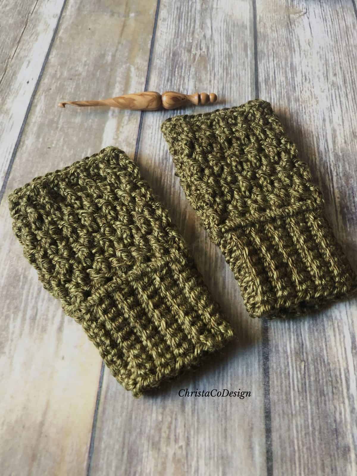picture of dark green crochet fingerless gloves on wood floor with wood crochet hook