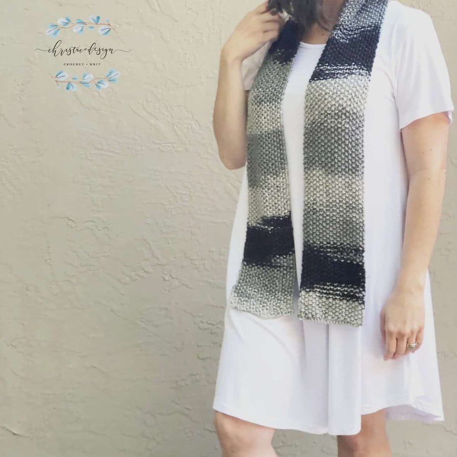 picture of woman in white dress with black grey ombre textured knit scarf on
