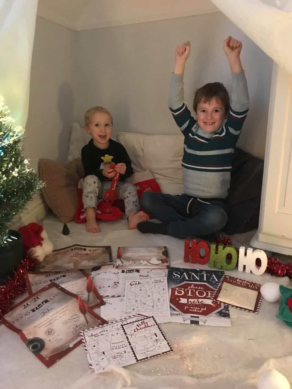 Jake with his arms up in celebration and william cheering whilst sat inside their grotto with their letters