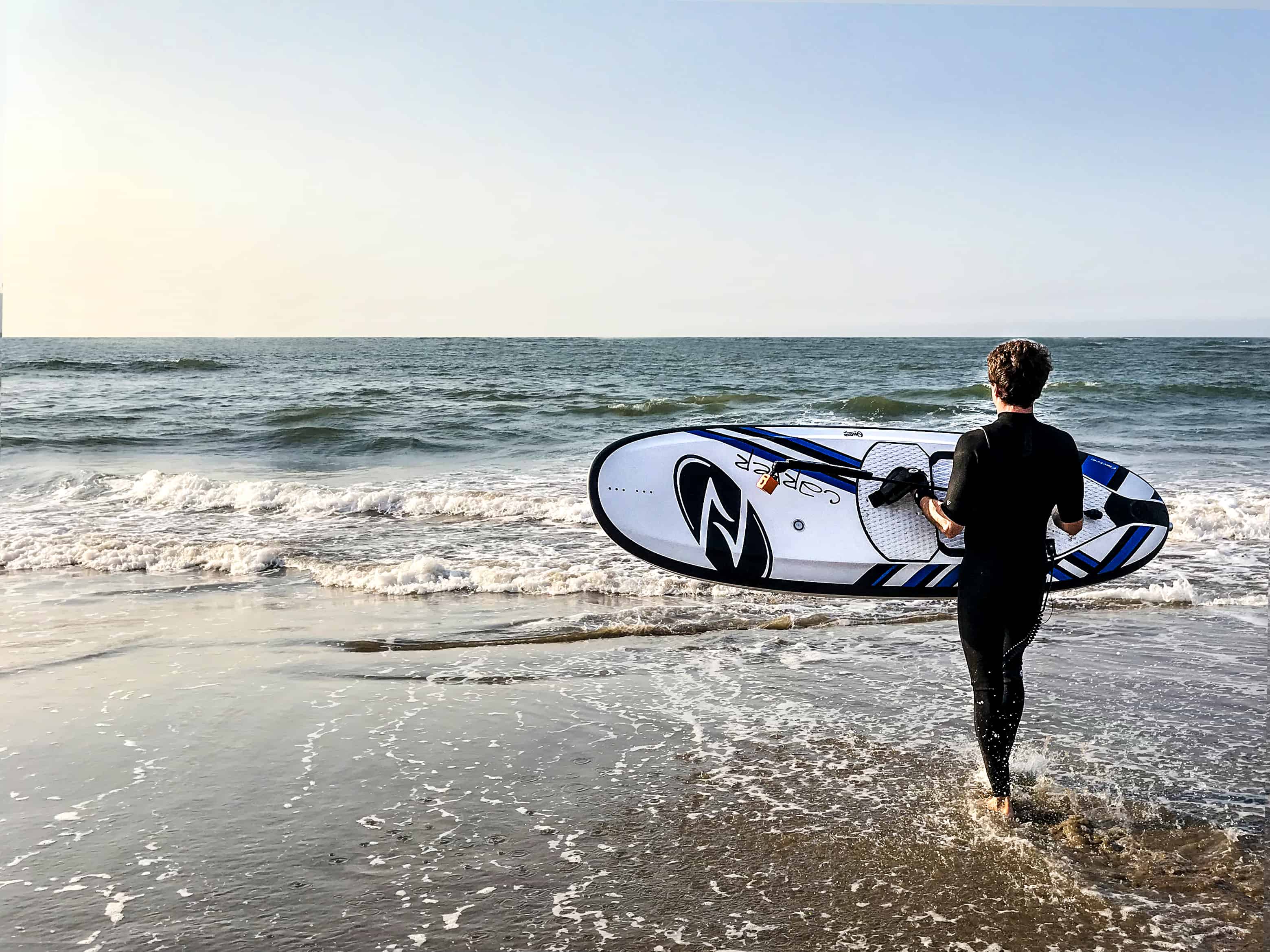 Guy carrying Onean Carver Electric Jetboard into the water