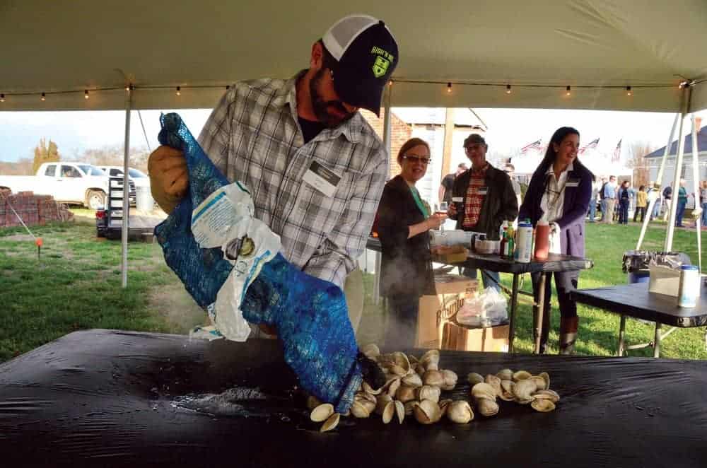 Chris Buck spreads freshly steamed Cherrystone clams on a table at the Barrier Islands Center Oyster Roast.