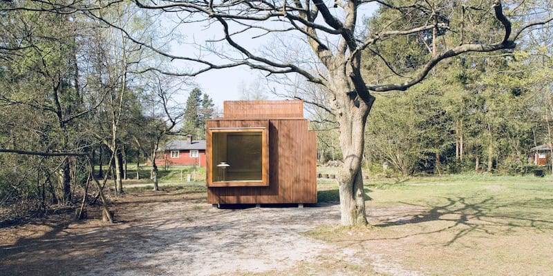 Das zeigt ein Minihaus auf einem schönen Grundstück. Vordergrund ist ein Baum zu sehen.