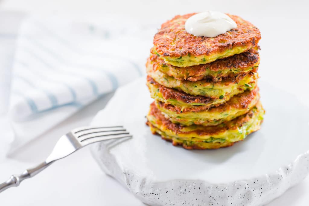 Fluffy Zucchini Pancakes Recipe A stack of delicious zucchini pancakes with a dollop of sour cream.