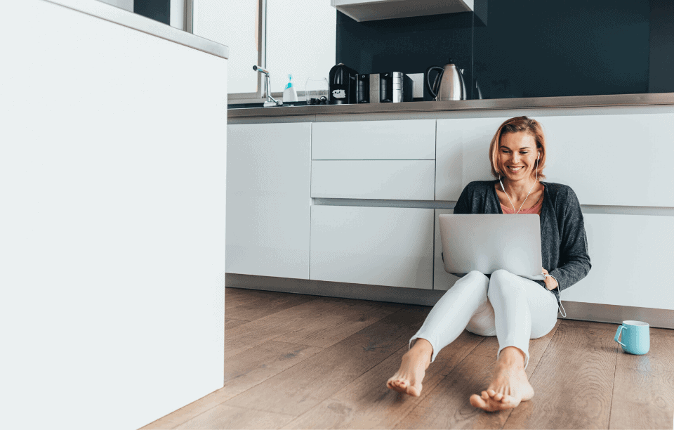 blond woman with headphones and laptop sitting on floor writing a landlord reference letter