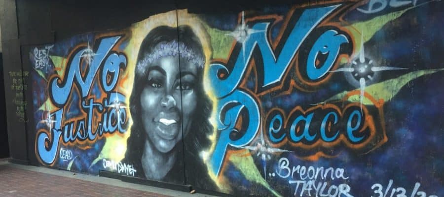 A spray painted mural depicts Breonna Taylor and the words No Justice No peace