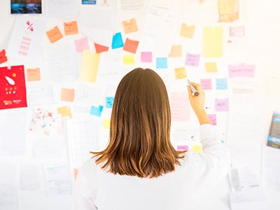Overwhelmed Business Woman Trying to Understand VoIP With Post It Notes on a Board in Front of Her