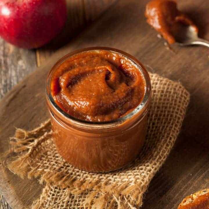 jar of apple butter sitting on cutting board with piece of burlap
