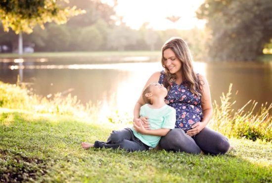Renee Barber a kansas city newborn photographer of Lambs and Lullabies Photography taking photos with her son on her back
