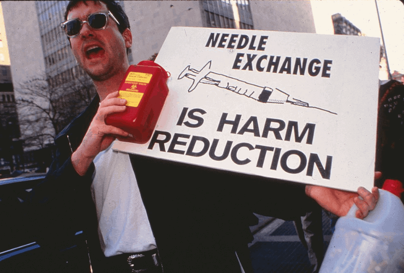 Alan Clear Lower East Side Harm Reduction Image of Alan Clear holding a sign that reads Needle exchange is Harm Reduction