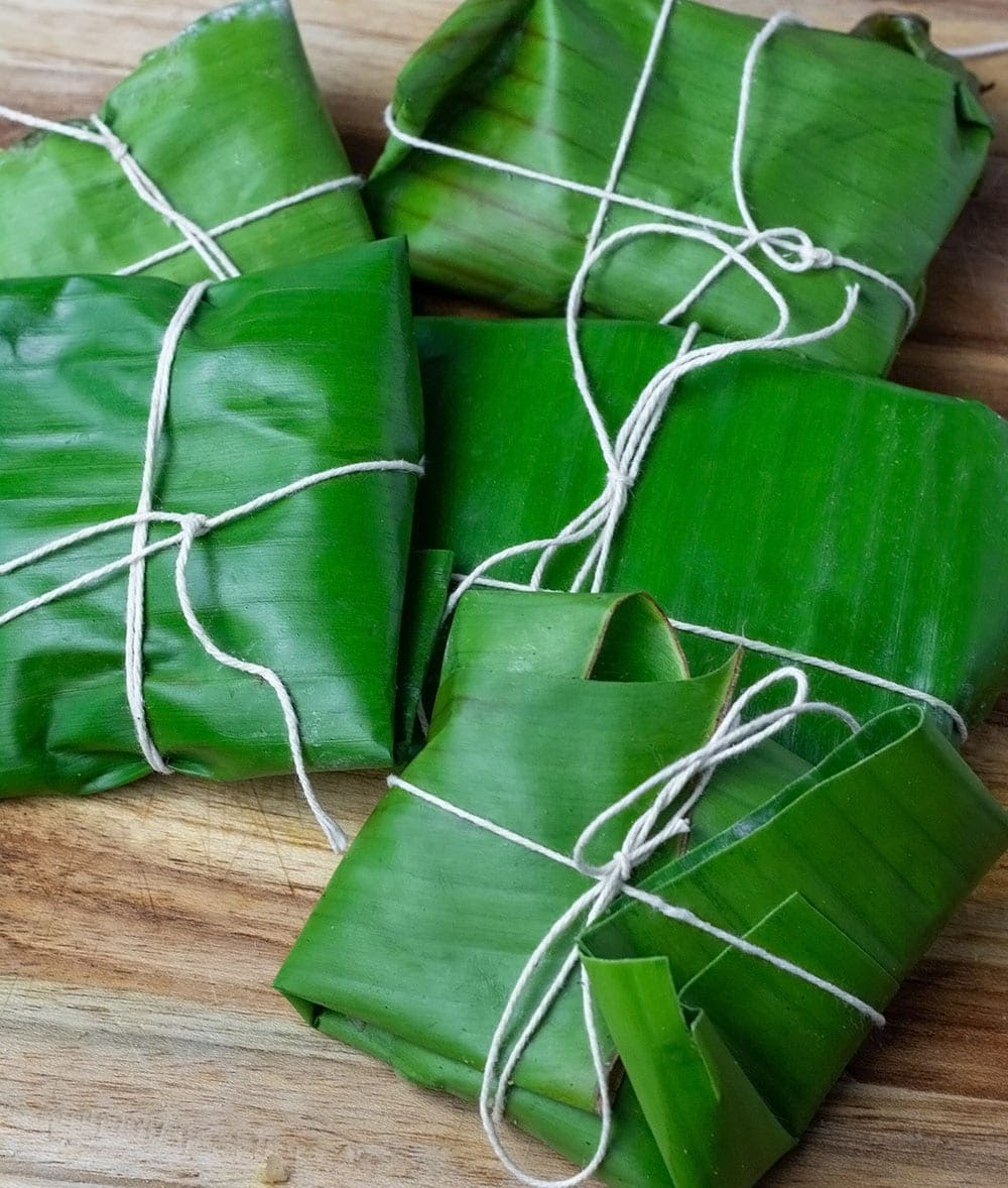 Blue draws wrapped in fresh banana leaves on a wooden cutting board